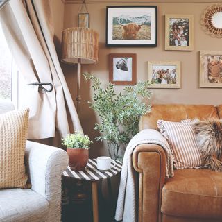 A light brown-painted living room with a gallery wall and a caramel brown leather sofa