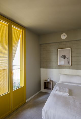 An all-white bedroom, with yellow-painted door