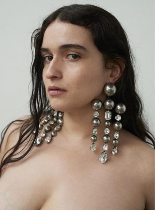 Model wears dangly earrings by Area