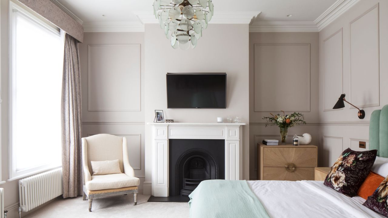 A stylish white bedroom, with a king size bed, white fireplace, and a flat screen TV