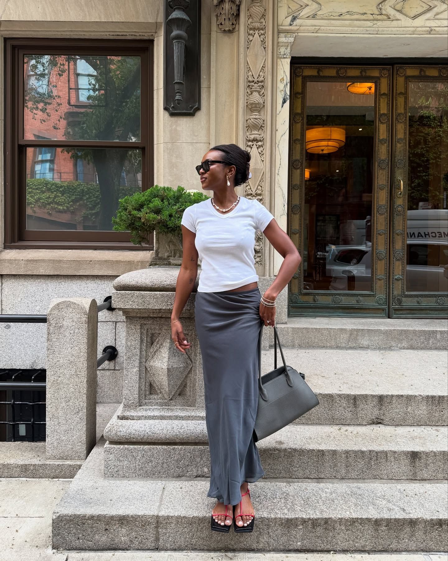 @devapollon wears a red pair of sandals with a grey maxi skirt and white T-shirt