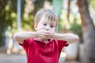 A child covering his mouth.