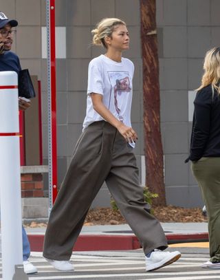 A photo of Zendaya wearing a vintage t-shirt featuring a print of artist Gilbert Young's painting titled "He Ain't Heavy."