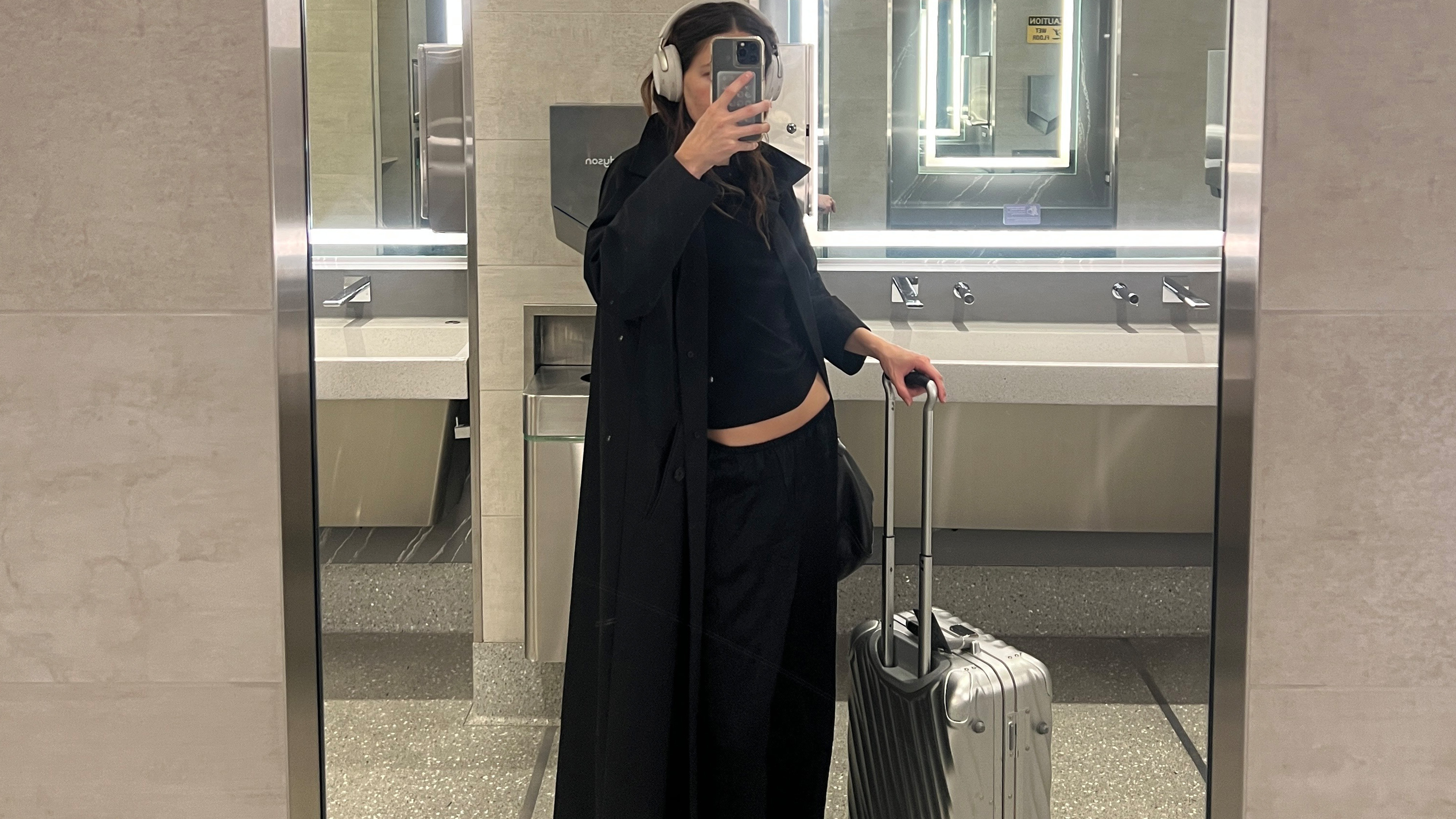 Eliza Huber at LGA Airport with her TUMI international carry-on suitcase.