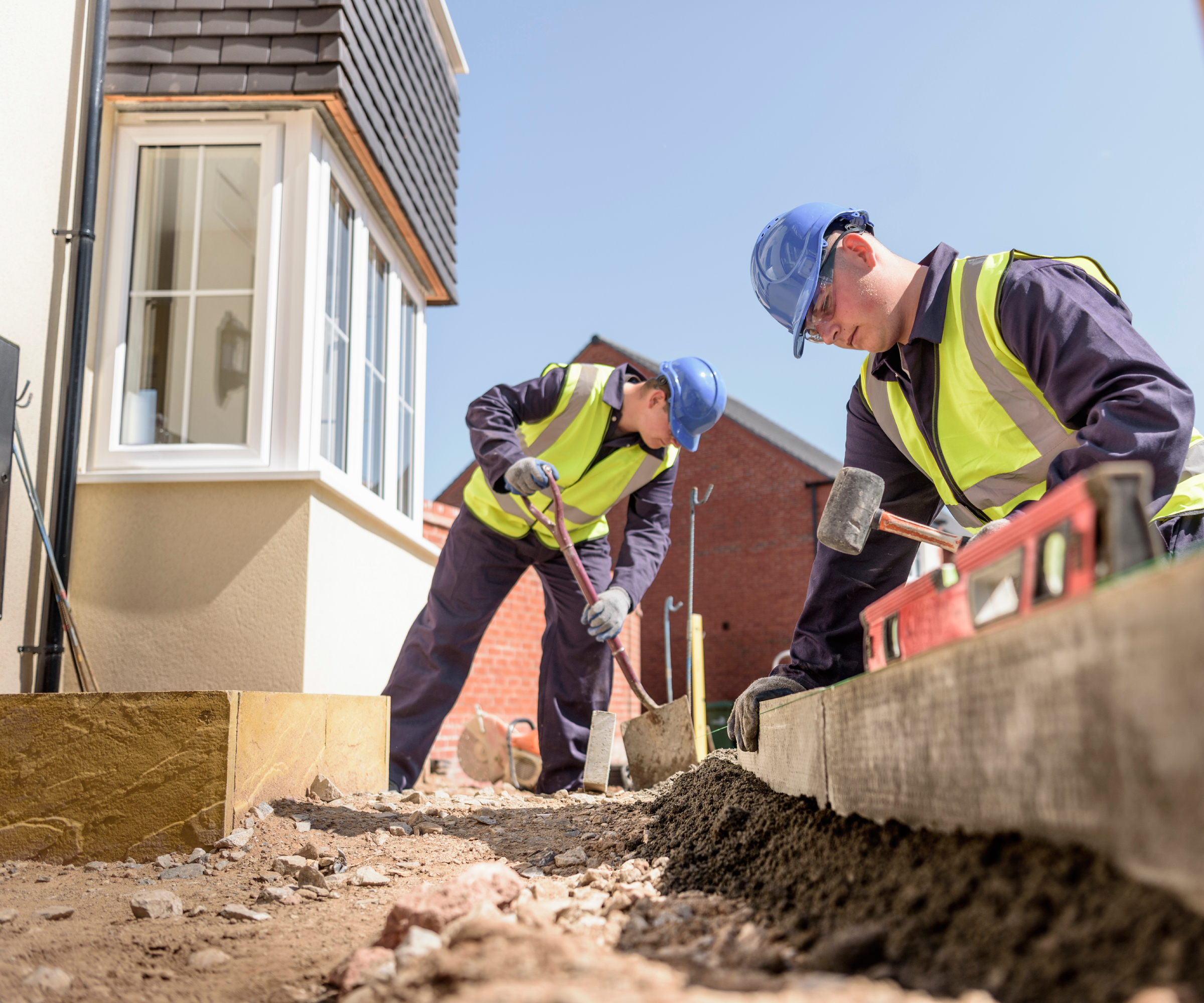 Two workmen working on the drive at the front of the house