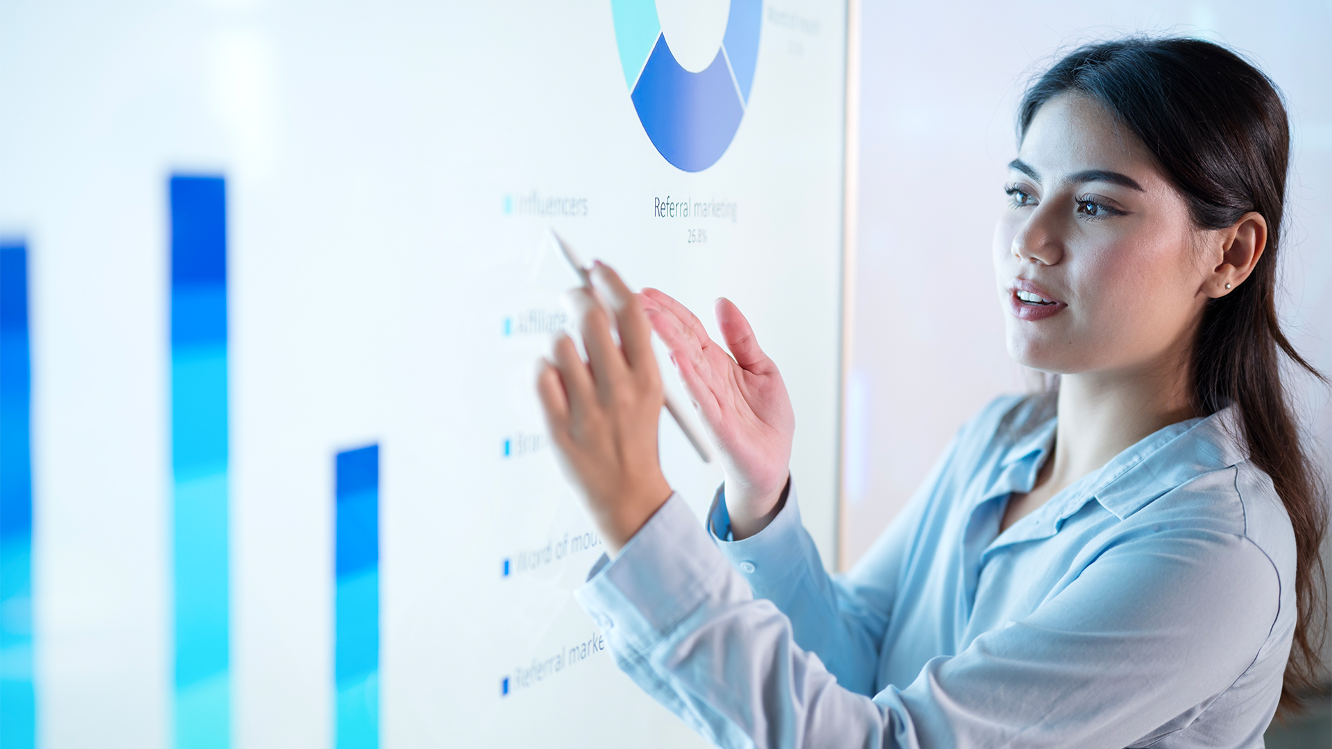 Female chief financial officer (CFO) showing statistics on a screen during a presentation. 