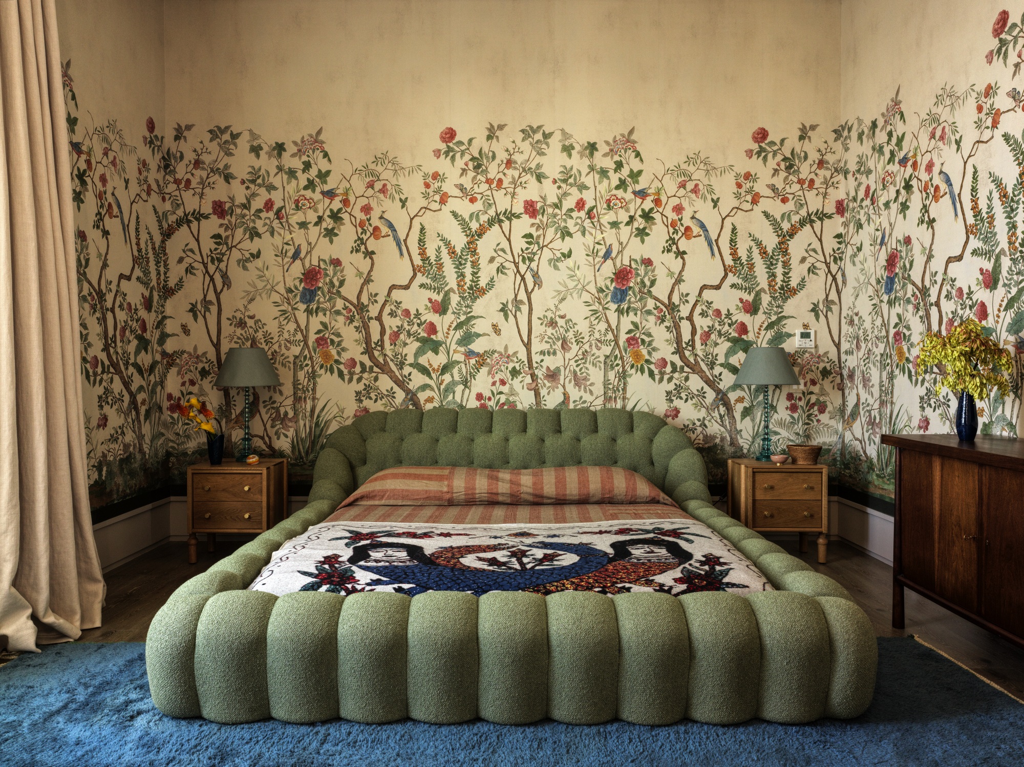 modern bedroom with yellow walls and botanical mural, blue carpet, green sculptural bedframe, yellow curtains, and timber dresser, timber side tables with blue lamps