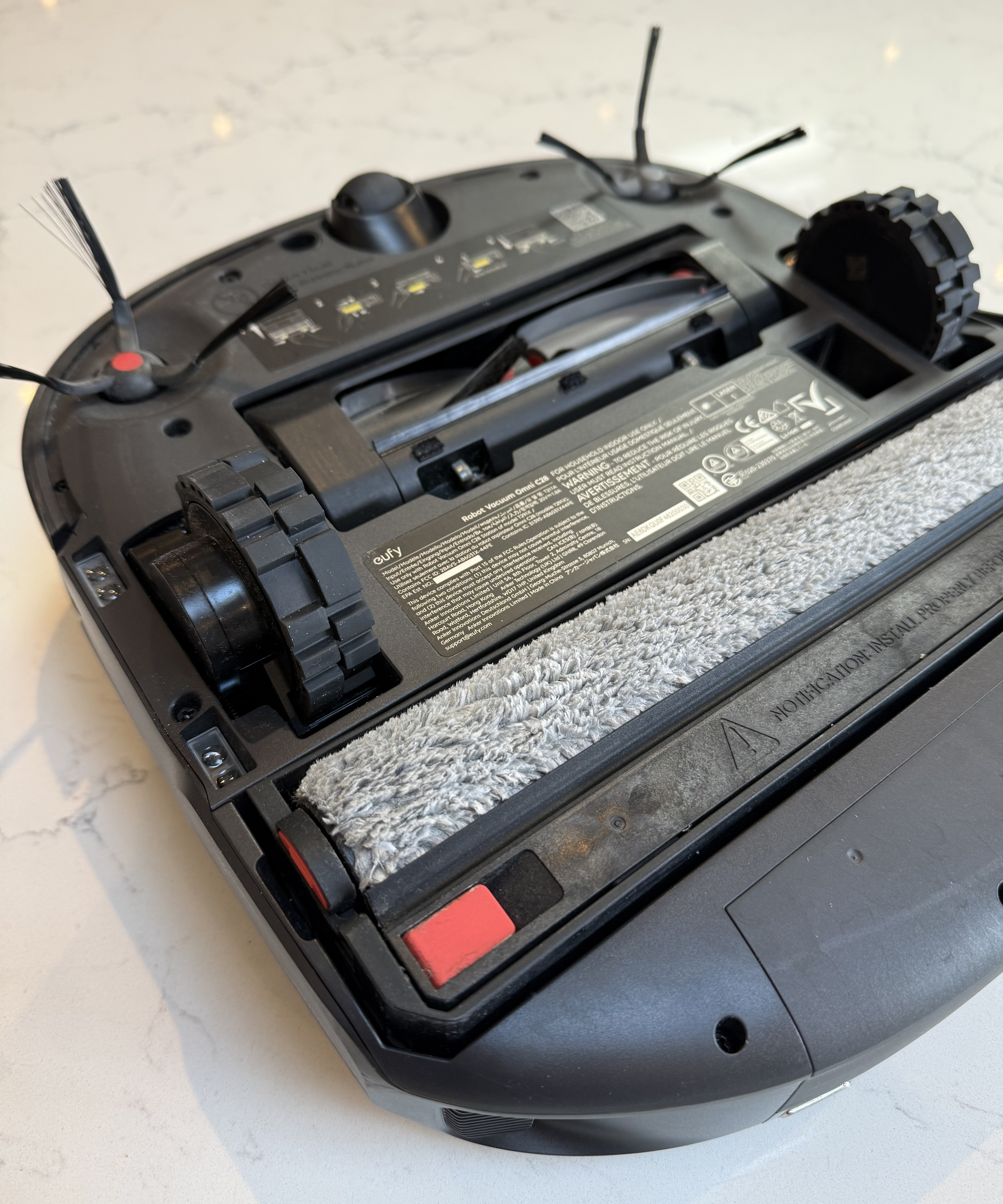 The underside of the eufy C28 showing the side brushes, the rubber brush rolller and the fabric roller mop