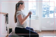 A pregnant woman uses a resistance band whilst sat on a Swiss ball
