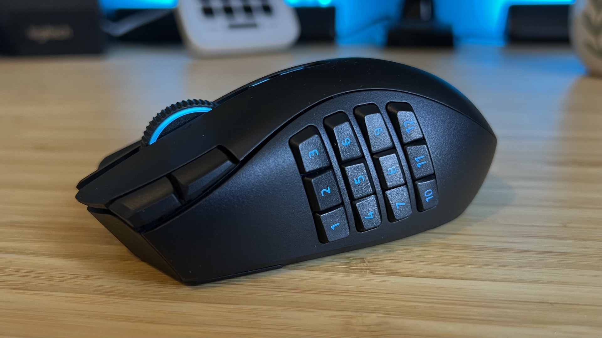 Razer Naga V3 Pro gaming mouse with 12-button side panel attached on a wooden desk with blue backlighting