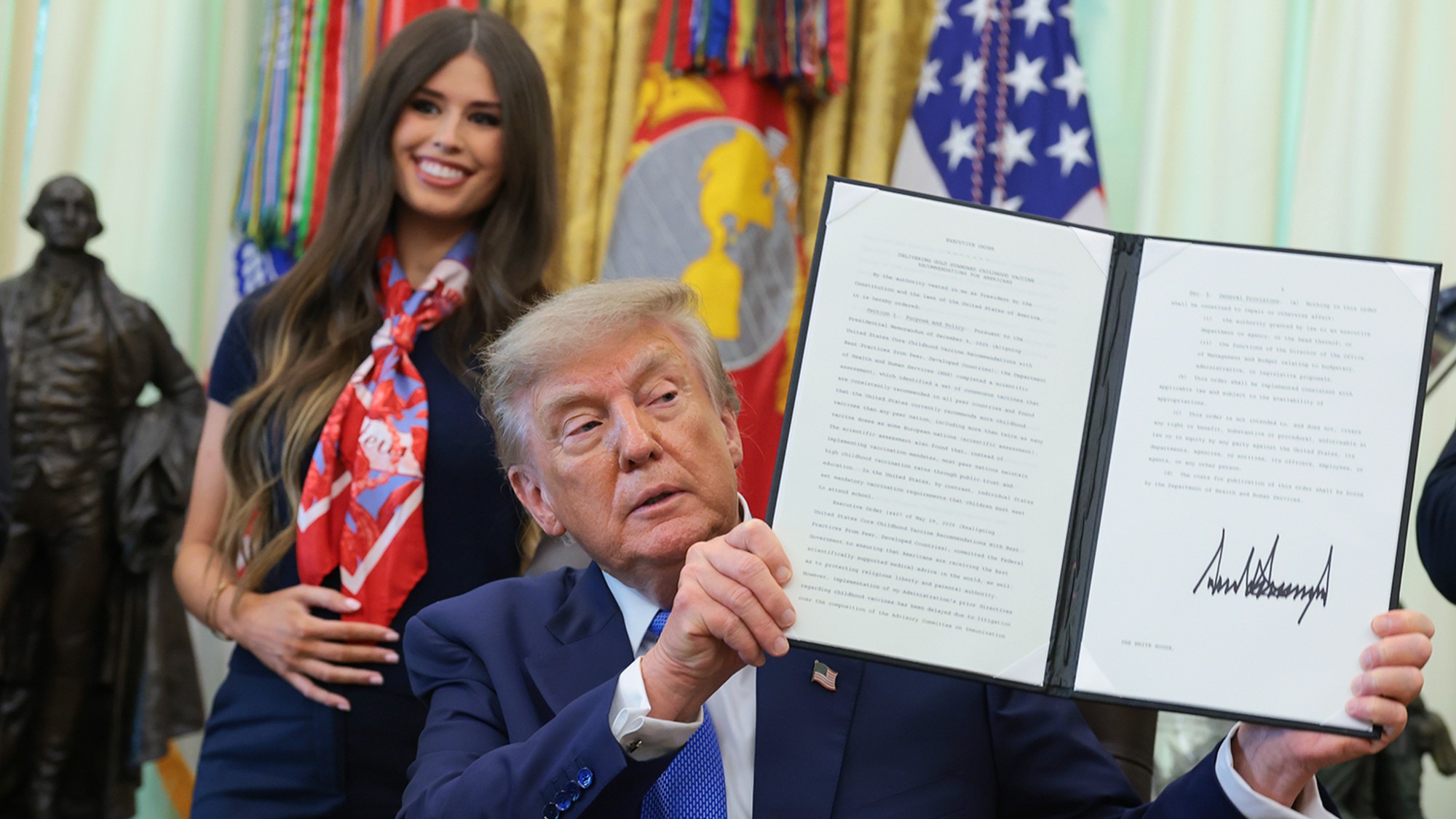 Trump holds up a paper with his signature