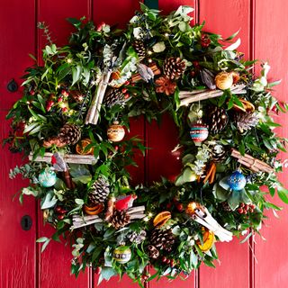 Green circle shaped plants with Christmas décor against a red wooden door