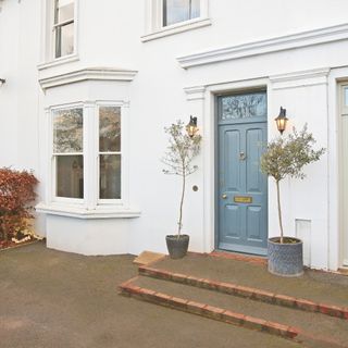 Exterior of a white house with driveway and blue front door