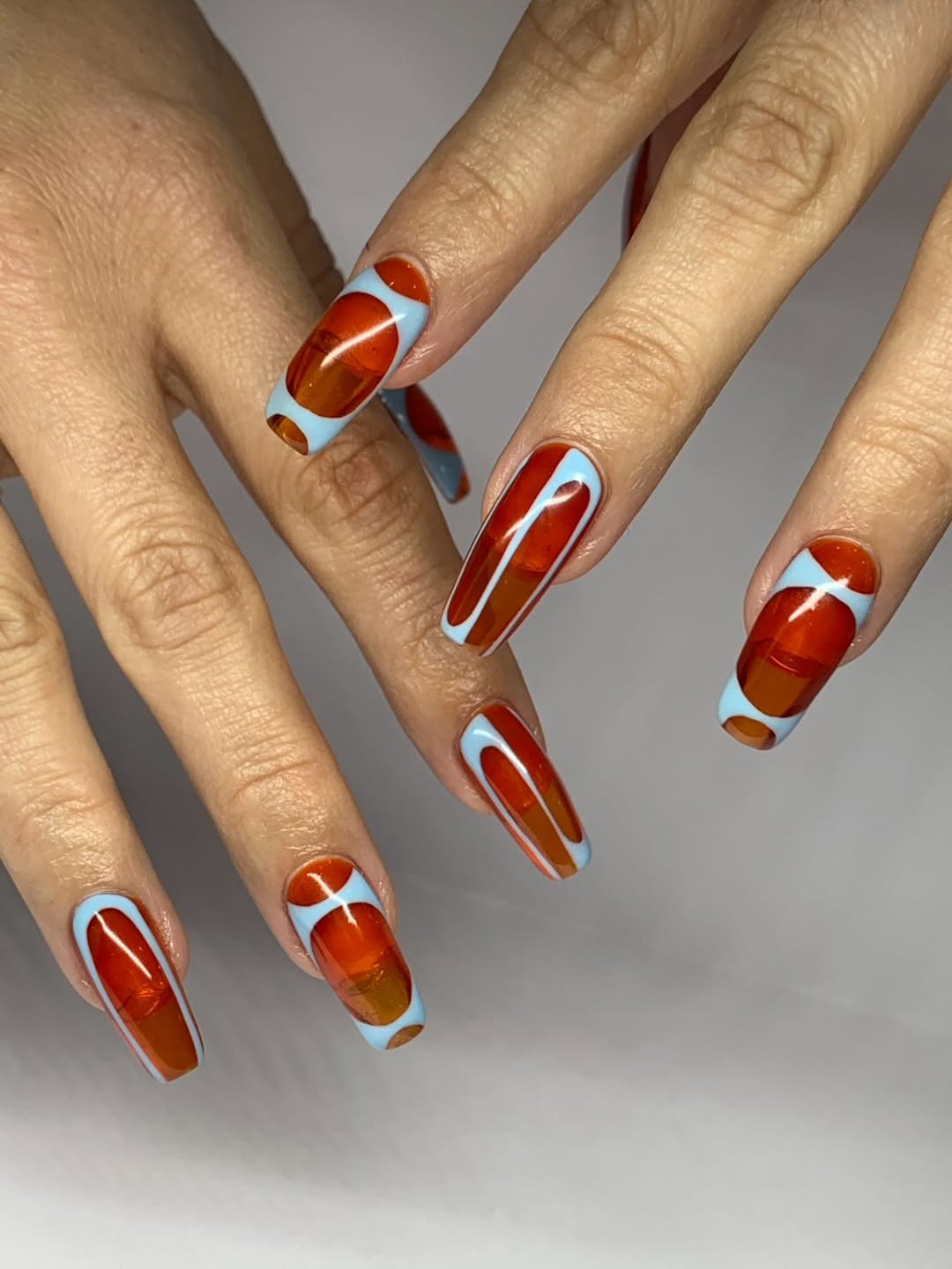 orange jelly nails with an abstract light blue design