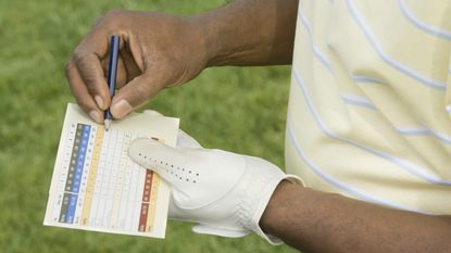 Golfer entering score on scorecard GettyImages-80509548