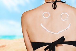 A woman wearing sunscreen on her back in the shape of a smiley face.