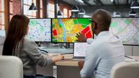 male and female sat at desks looking at three screens showing land registry documents