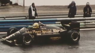 A still from Senna of a black race car on a track.