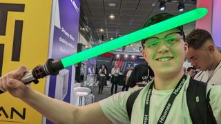 Hamish holding a green glowing lightsaber in front of his face, its glow is reflected in his glasses