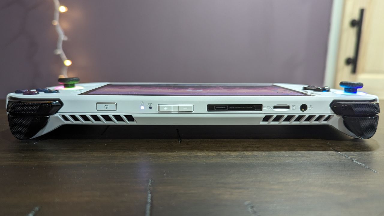 Asus ROG Ally Z1 on a brown table, highlighting the ports and inputs on top of the device, including the headphone jack, microSD card slot, volume buttons, USB Type-C, and power button.
