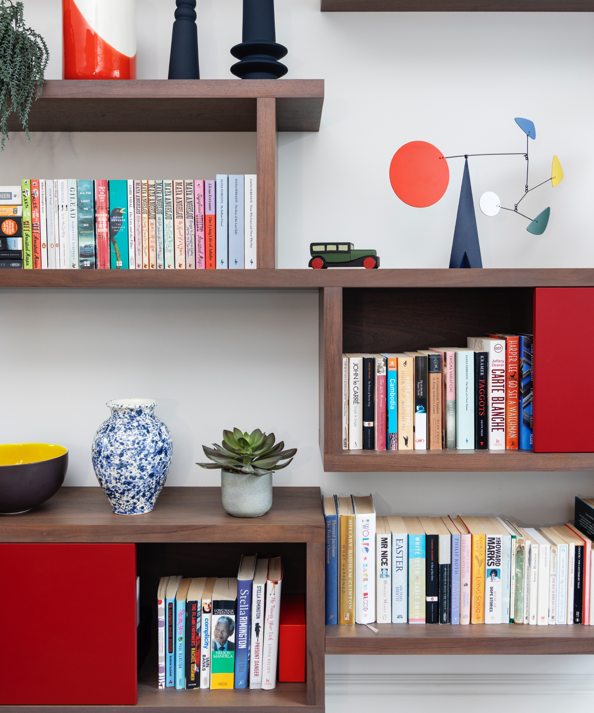modernist living room block wall mounted shelving with red, blue and white doors, open shelving, books, ornaments