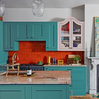 kitchen cabinets in blue and pink with a red tiled splashback