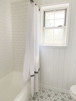 White guest bathroom with wall paneling and matching black rim mirrors