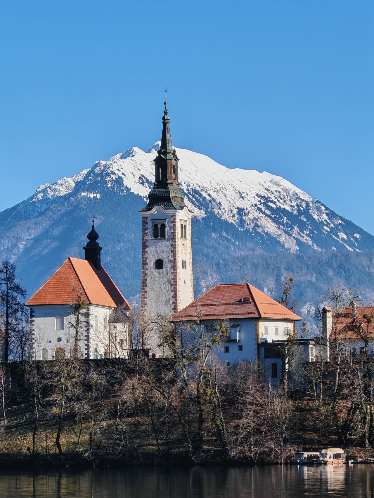 Castle on Lake Bled with a snow capped mountain in the background