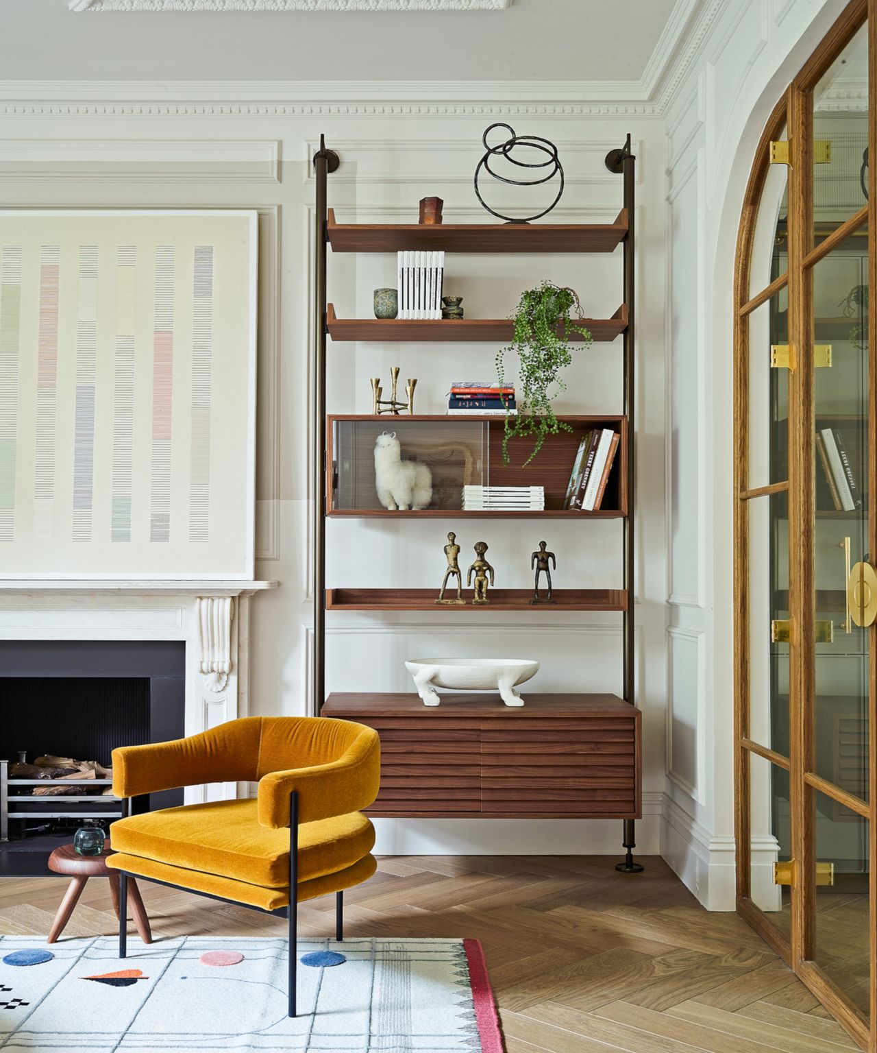 Neutral living room with plush mustard armchair, mid-century style cubby unit, and graphic rug