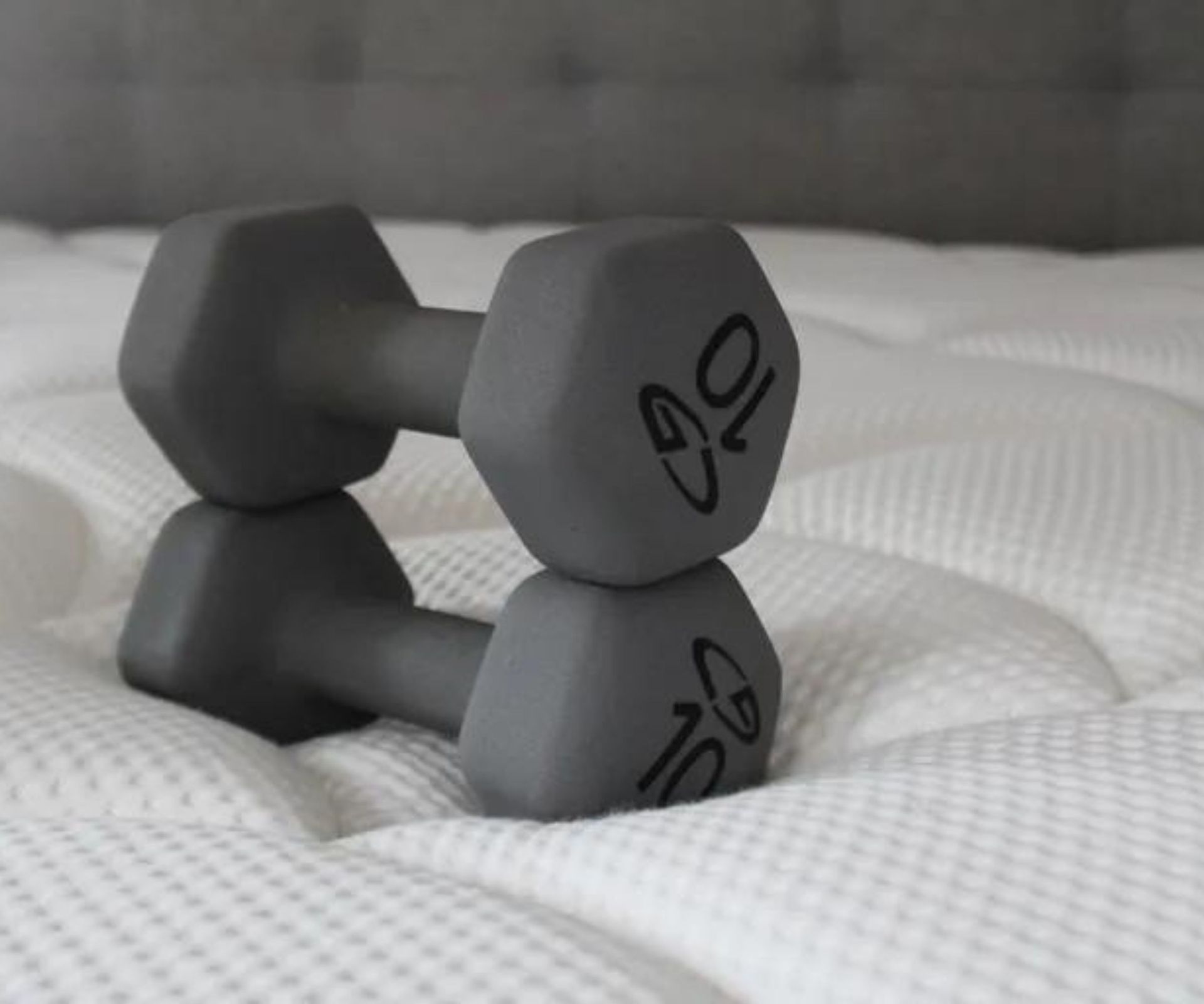 Two dumbbells on the DreamCloud Luxury Hybrid Mattress.