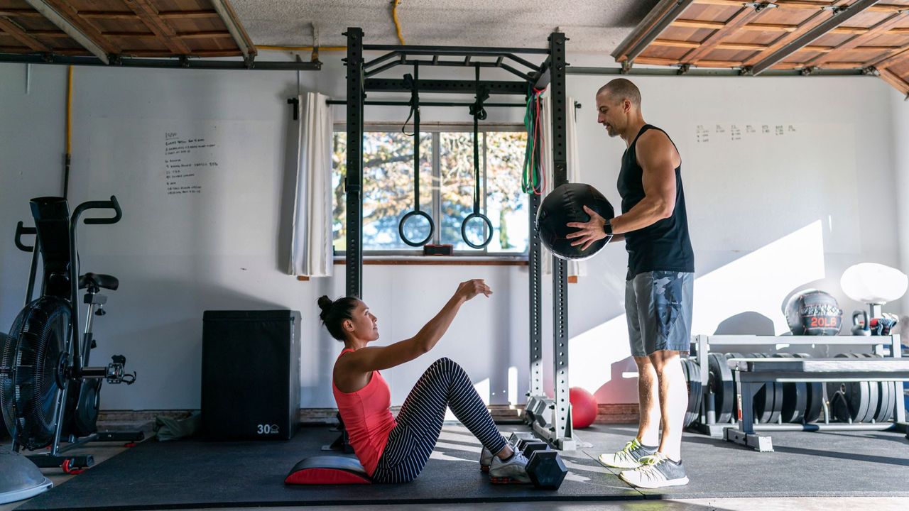 A woman exercising in a home gym with a personal trainer 