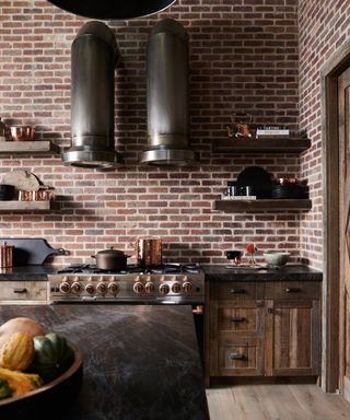 An industrial-style kitchen with brick walls and a unique metal range hood