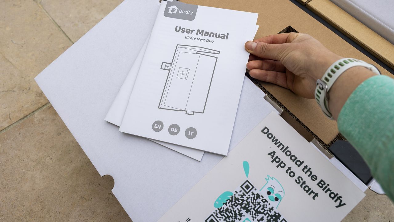 The Birdfy Nest Duo box being opened and user manual picked up