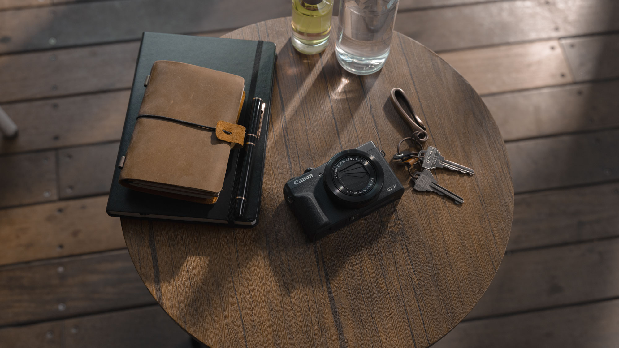 Canon PowerShot G7 X Mark III Anniversary Edition in graphite, on a circular wooden table alongside a journal