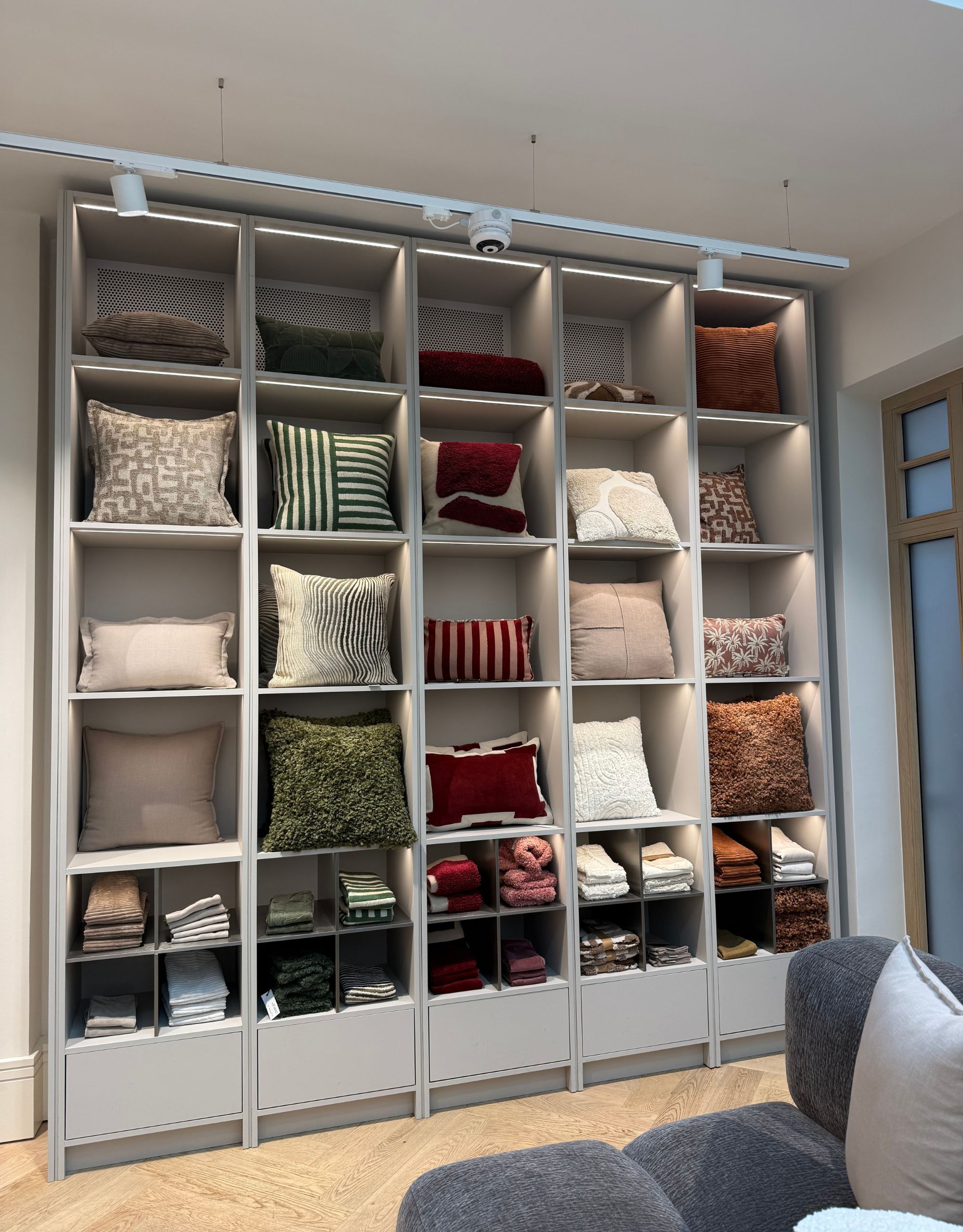 A shelving display filled with all different shapes and colors of cushions
