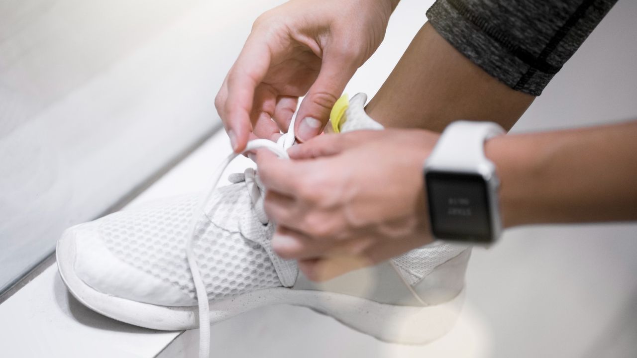 Woman tying her running shoes wearing a watch