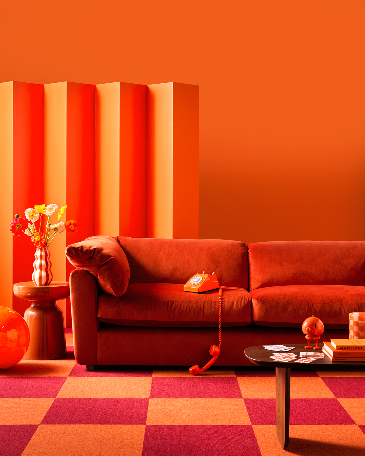 Image of a bright orange room with an orange room divider, orange and red checkerboard floors, a burnt orange sofa, and an orange side table.