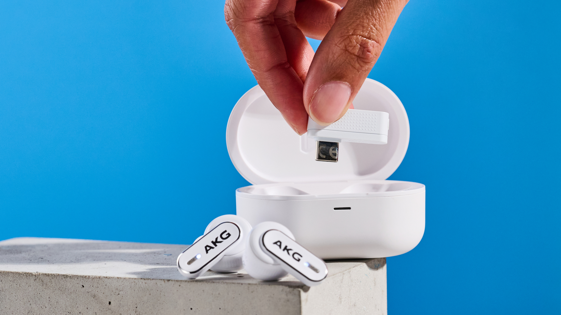 the akg n5 hybrid earbuds by harman in white, shown in their charging case with accessories and without