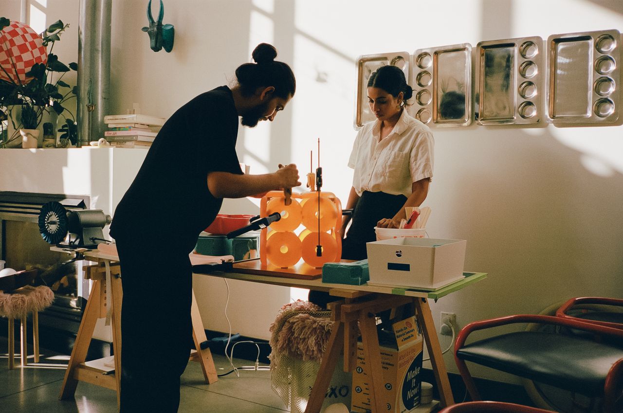 Two young artisans at work in their creations-filled, naturally lit studio.