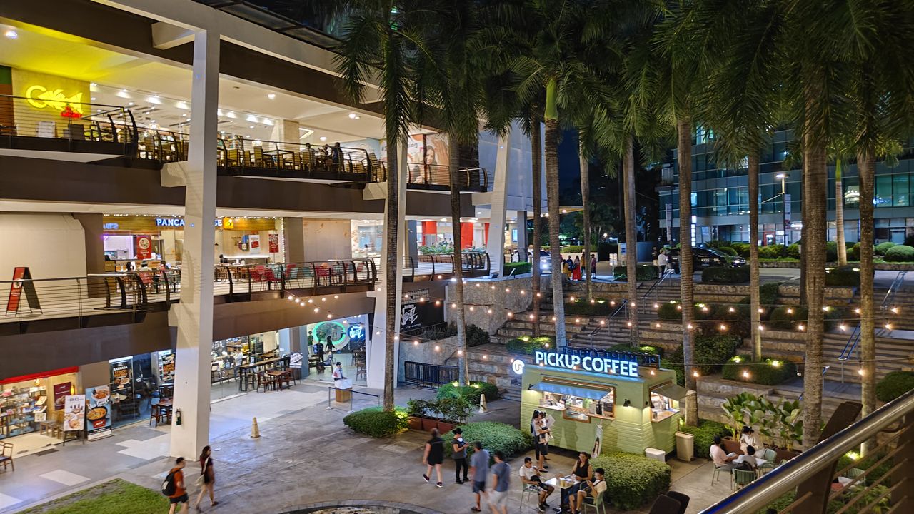 A bustling mall with shoppers strolling around and browsing through various stores.