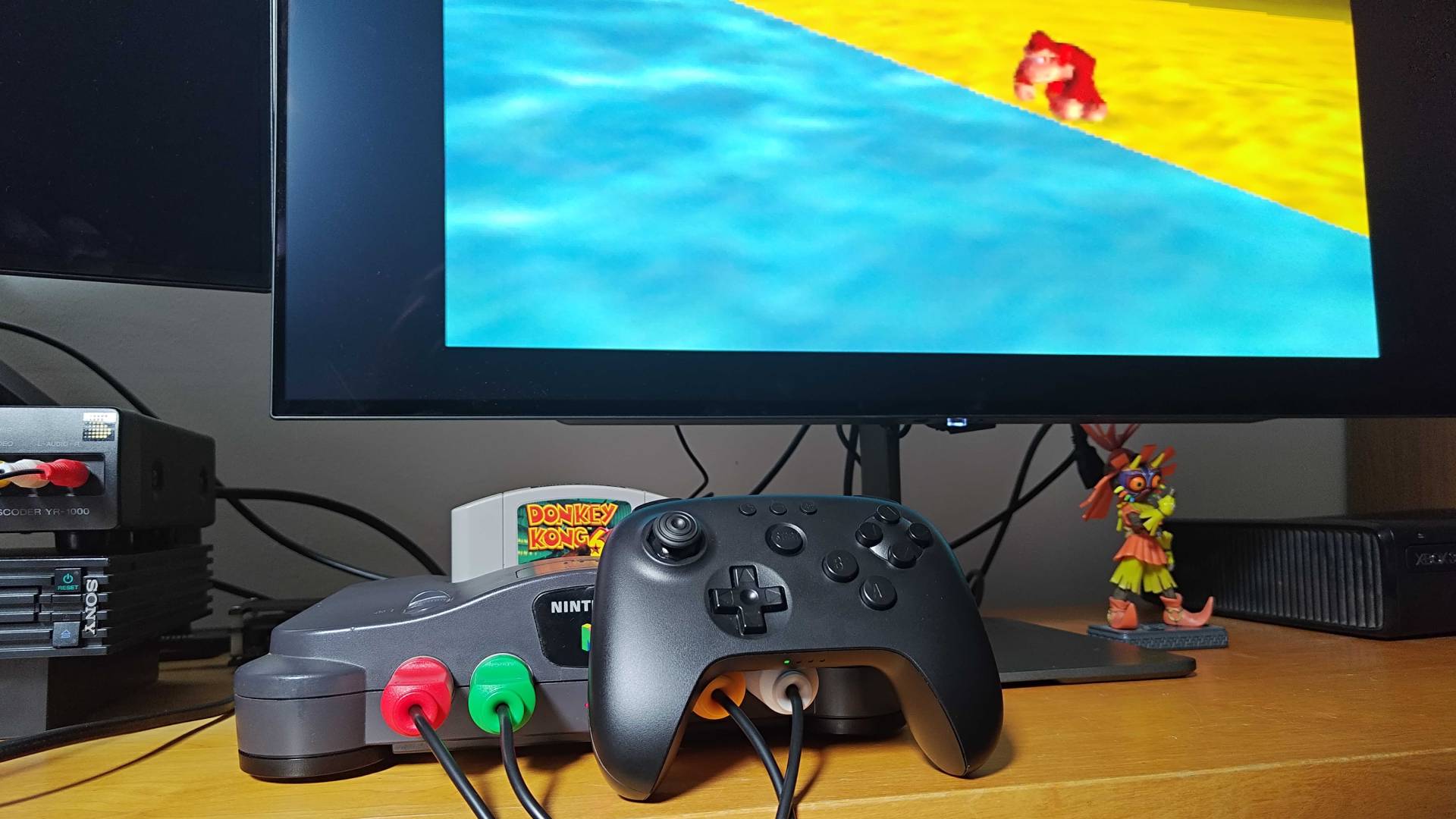 Close up of 8Bitdo N64 Bluetooth controller leaning against Nintendo 64 running Donkey Kong 64.