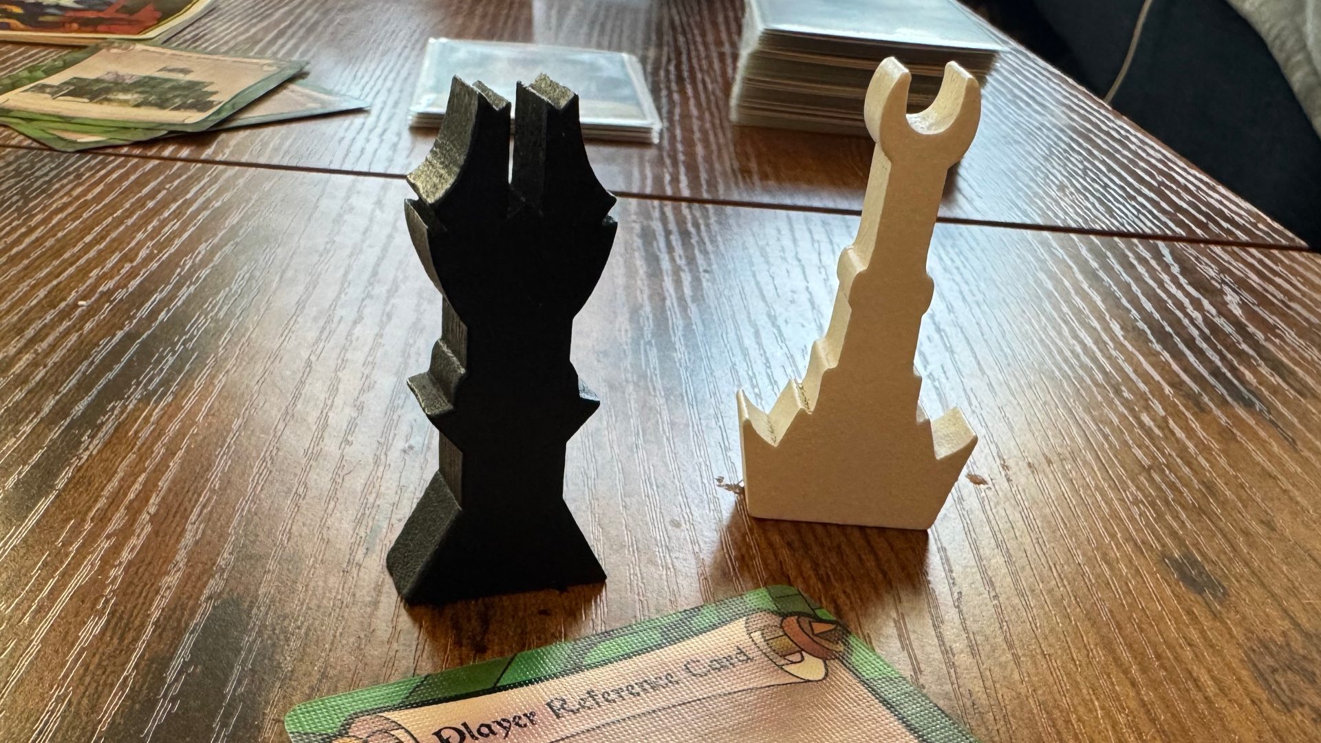 Two tower tokens from The Two Towers Trick-Taking Game on a wooden surface