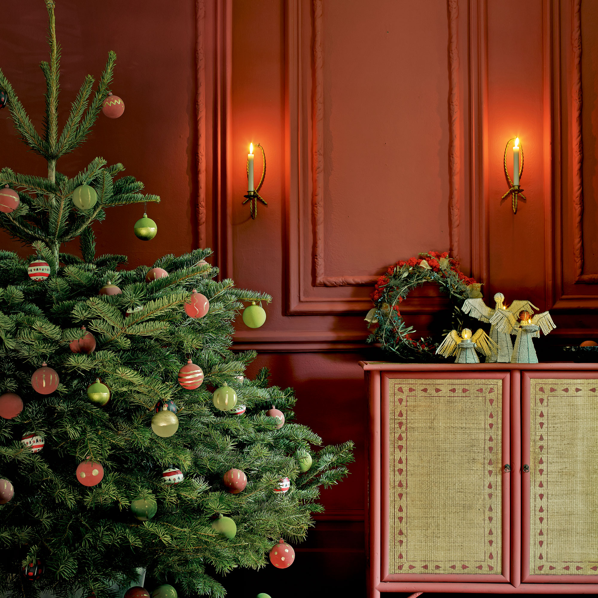 Red panelled room with a christmas tree decorated with green and red baubles.