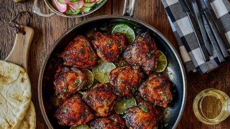 The Hestan NanoBond Skillet on a wooden counter, filled with fried chicken chunks and lime slices