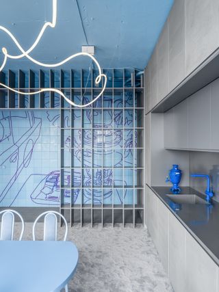 A blue and grey kitchen with bright blue faucet