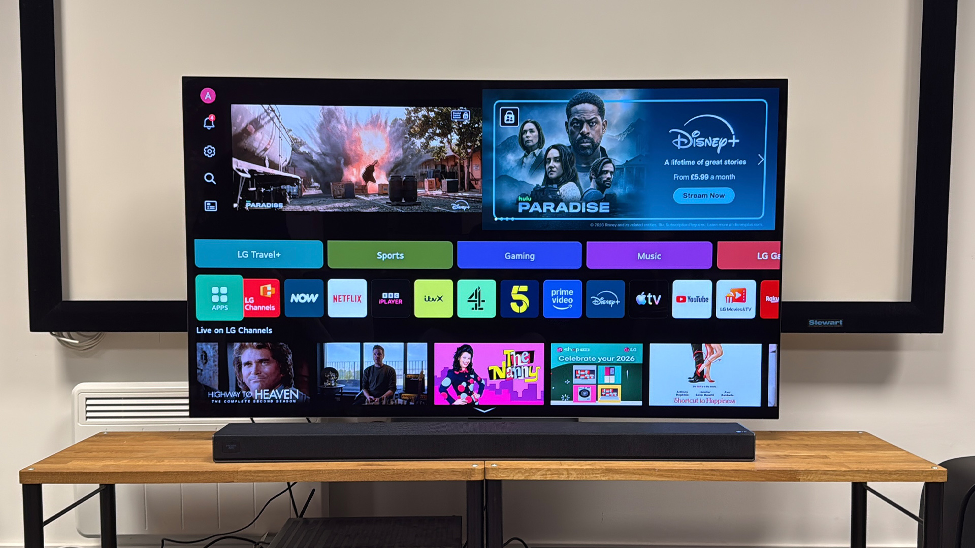 LG Sound Suite H7 soundbar on wooden AV rack below LG TV