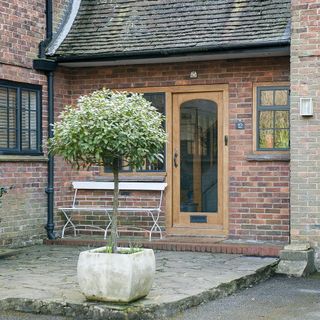 house with brick wall wooden door frame and pottedtree