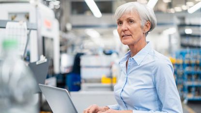 Senior businesswoman using laptop in a factory