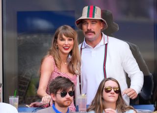 Taylor Swift and Travis Kelce wearing red and white outfits standing next to each other at the US Open