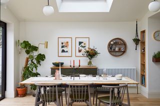 Lea-Wilson house: dining area under rooflight with upcycled wood table, painted wood chairs, green painted sideboard and abstract prints in background